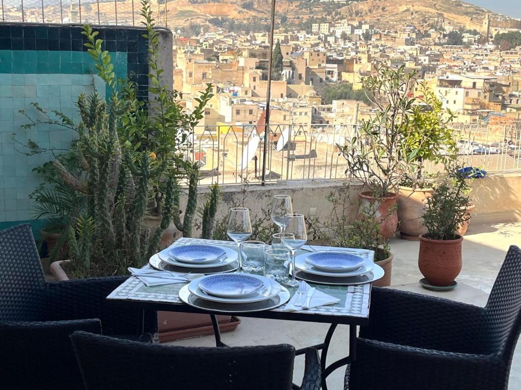 une table avec des assiettes et des verres à vin sur un balcon dans l'établissement Riad Palais Bahia Fes, à Fès