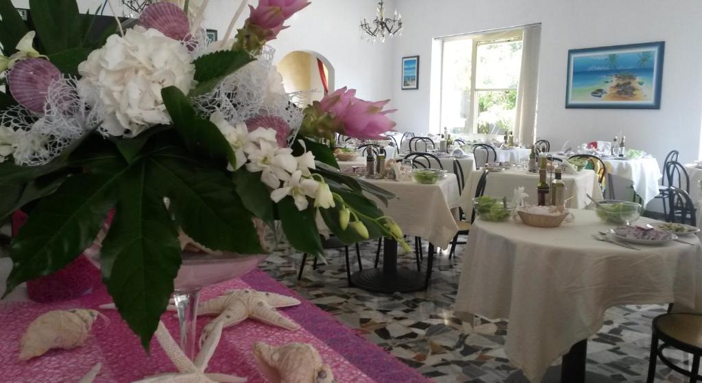 une salle à manger avec des tables avec des fleurs blanches et roses dans l'établissement Hotel Camelia, à Rimini