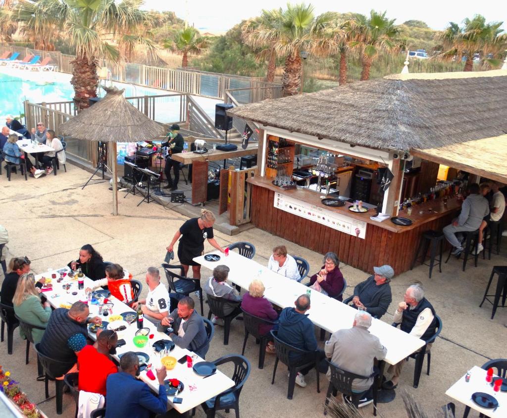 un groupe de personnes assises à table dans un restaurant dans l'établissement Camping Bleu Marine, à Sérignan