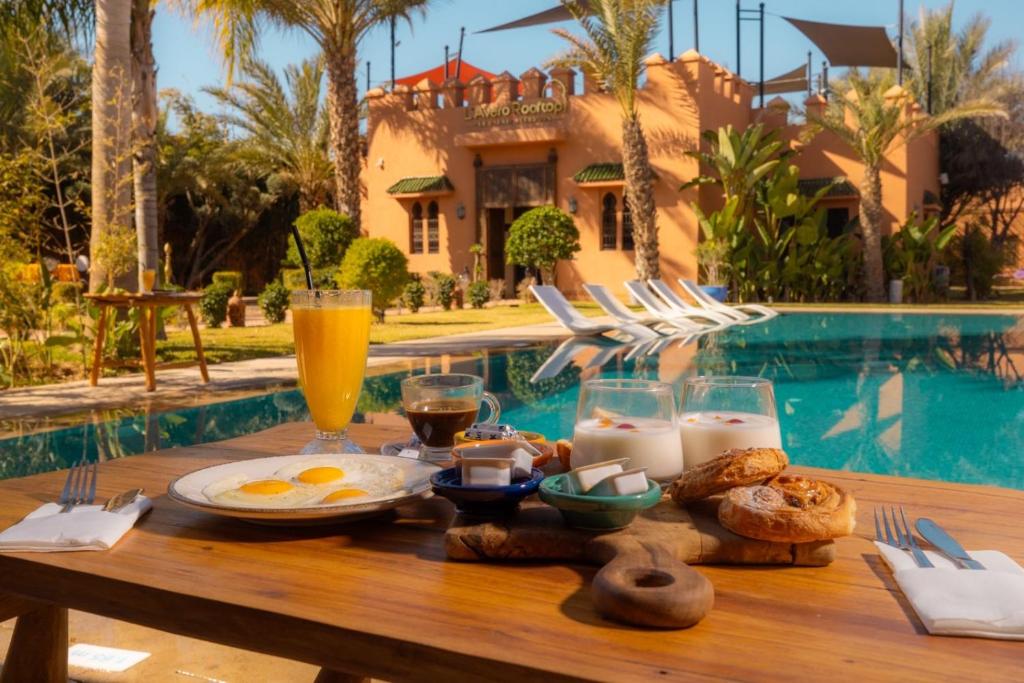 - une table avec petit-déjeuner et boissons à côté de la piscine dans l'établissement Le Palais Averroes - Adults Only, à Marrakech