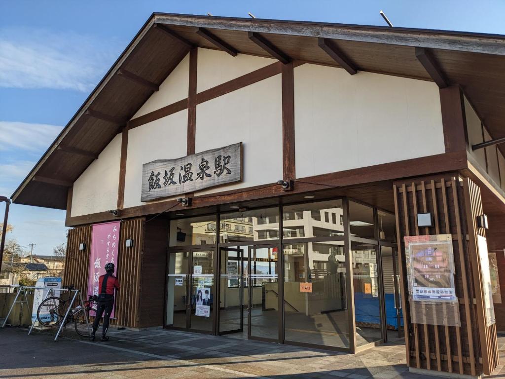 une personne debout à l'extérieur d'un bâtiment dans l'établissement 温泉屋ひろすけ旅館, à Fukushima
