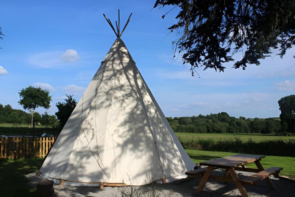 une tente pyramidale avec une table de pique-nique dans un champ dans l'établissement Le Val Insolite, à Lieuron 11 autres photos
