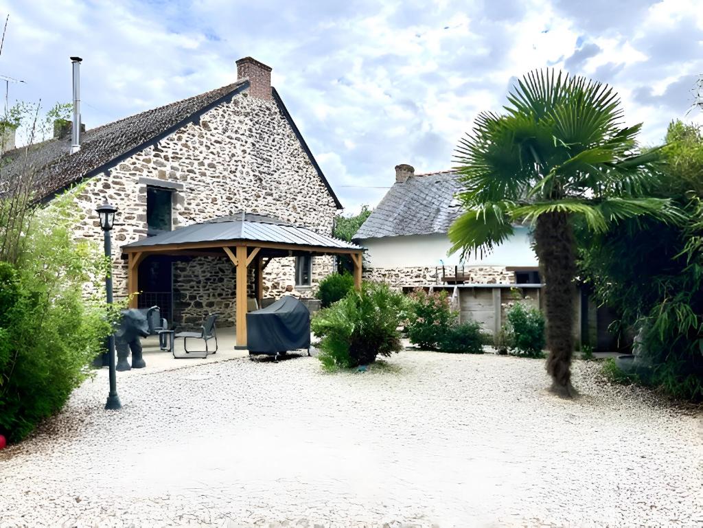 une maison avec un parasol et un palmier dans l'établissement Le Val Insolite, à Lieuron