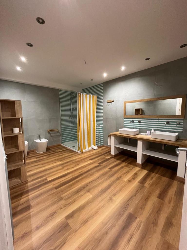 une grande salle de bain avec parquet et un grand miroir dans l'établissement Incanto Chic Appartamento in Villa, à Sacrofano