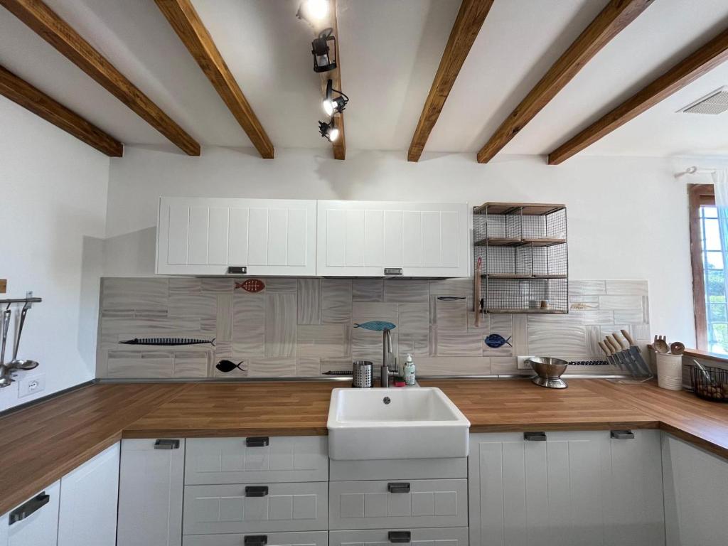 une cuisine avec des armoires blanches et un évier dans l'établissement Incanto Chic Appartamento in Villa, à Sacrofano