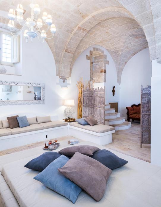 un salon avec des murs blancs et un grand canapé dans l'établissement Villa Favorita Luxury - Italia Monopoli Puglia Trullo, à Monopoli
