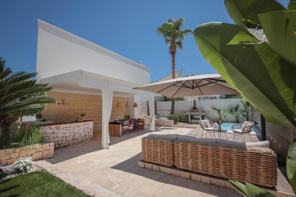 un patio avec une table et un parasol dans l'établissement Nilu al Mare - Villa pool & sea Monopoli, à Monopoli