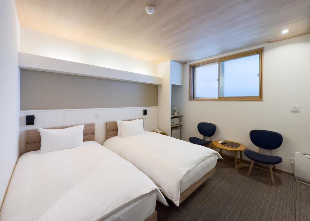 une chambre d'hôtel avec deux lits et une fenêtre dans l'établissement Yuno Yado Shoei, à Kyoto