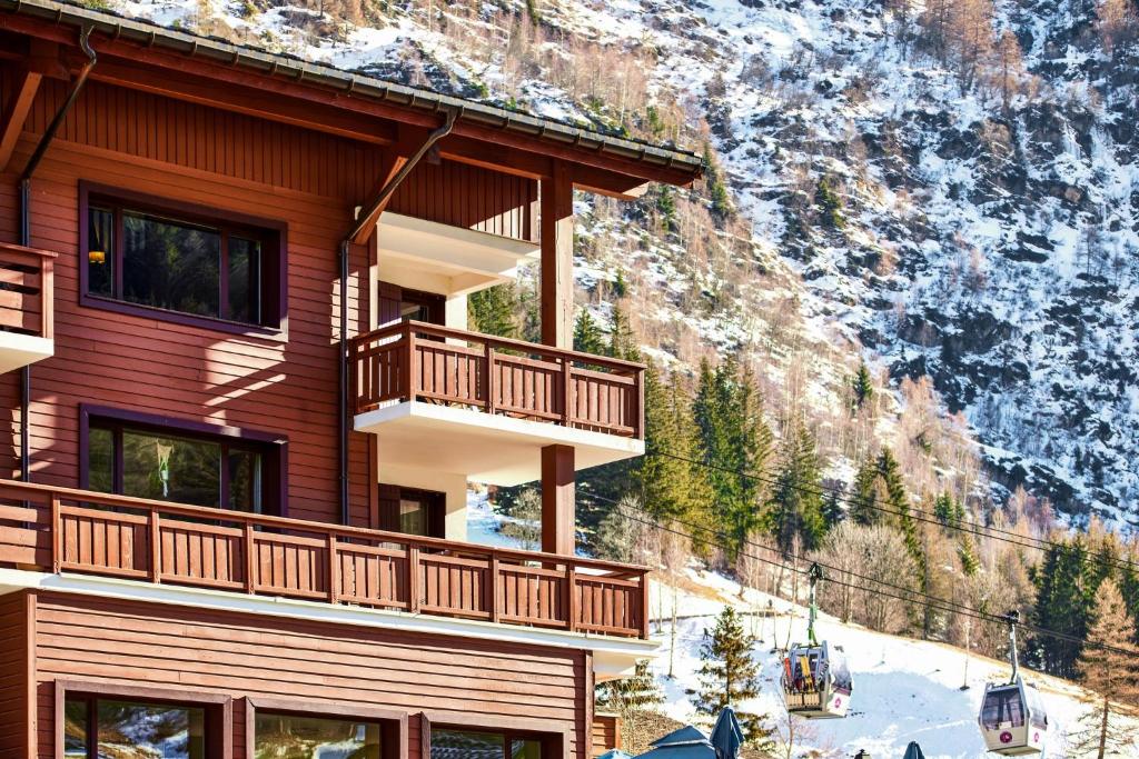 un bâtiment avec des balcons sur le côté d'une montagne dans l'établissement Charming Apartment Chamonix Valley, à Vallorcine