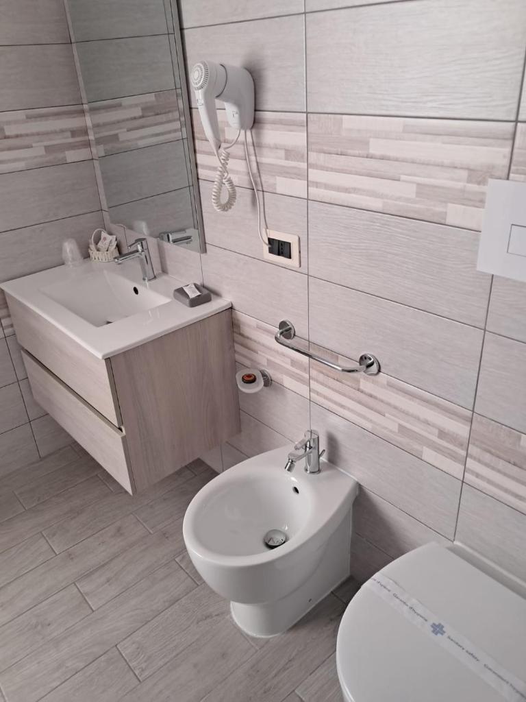 une salle de bain blanche avec toilettes et lavabo dans l'établissement Hotel Palace Gioia Tauro, à Gioia Tauro