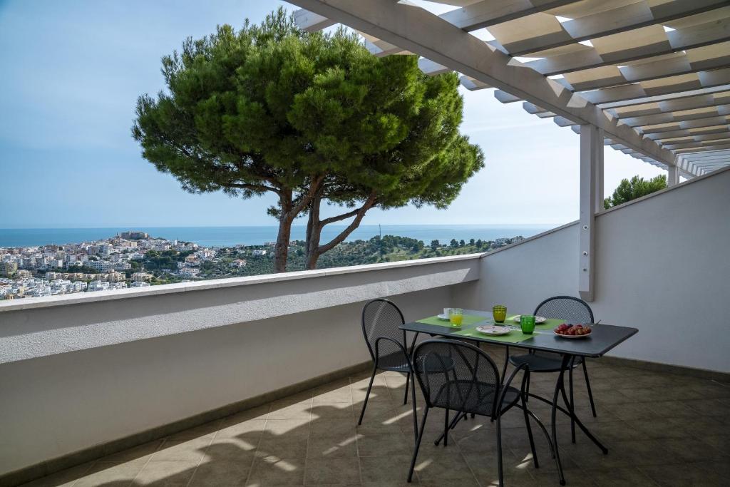 une table et des chaises sur un balcon avec un arbre dans l'établissement Residence Chiesiola, à Vieste