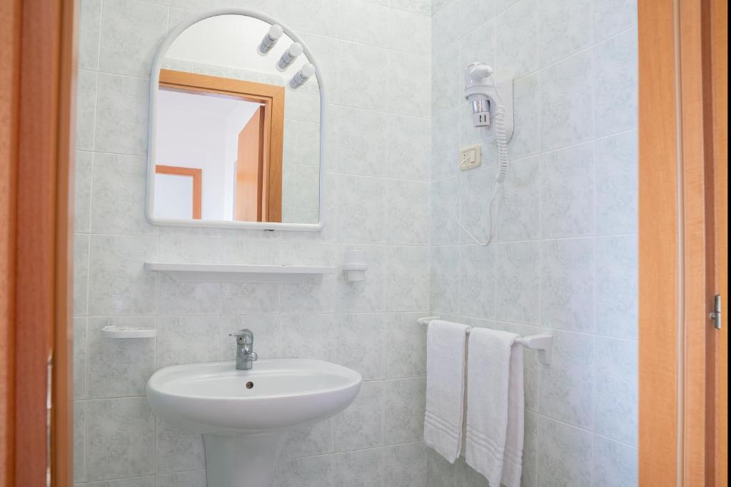 une salle de bain blanche avec un lavabo et un miroir dans l'établissement Residence Chiesiola, à Vieste