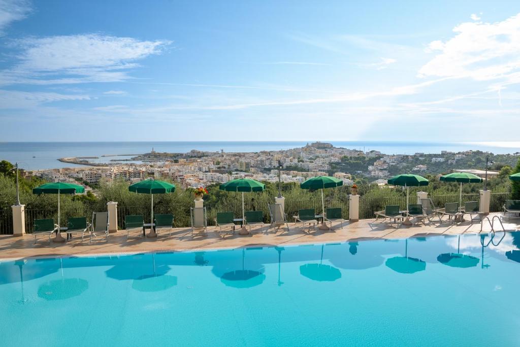 une piscine avec des parasols verts et une ville dans l'établissement Residence Chiesiola, à Vieste