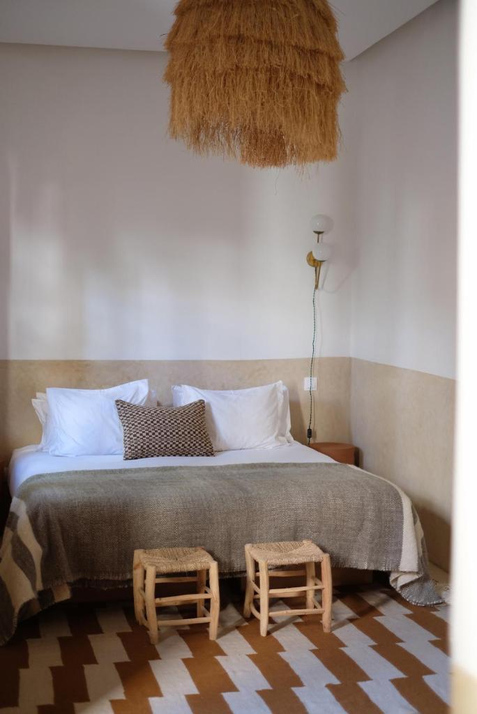 - une chambre avec un grand lit et deux tabourets dans l'établissement Riad L'Atelier, à Marrakech
