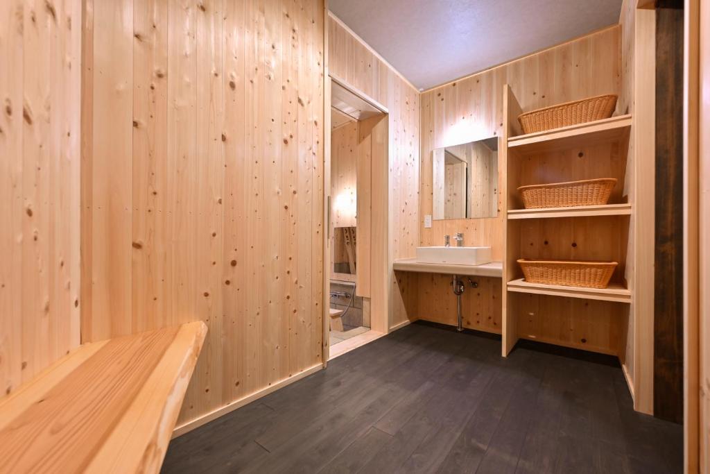 La salle de bains est pourvue de murs en bois et d'un lavabo. dans l'établissement うり房旅館仲通り うら房, à Kusatsu