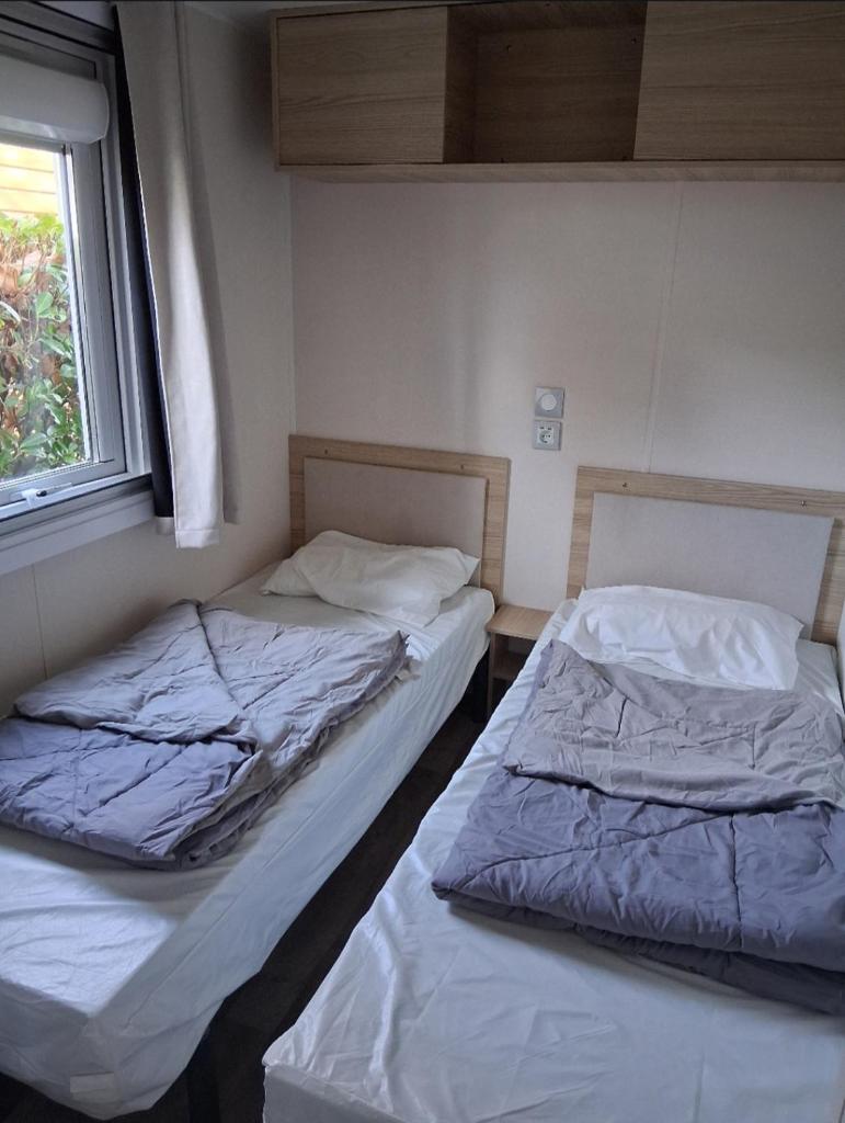 deux lits côte à côte dans une pièce dans l'établissement Charmant mobil-home N°698 3ch tout confort au calme, à Gastes 14 autres photos