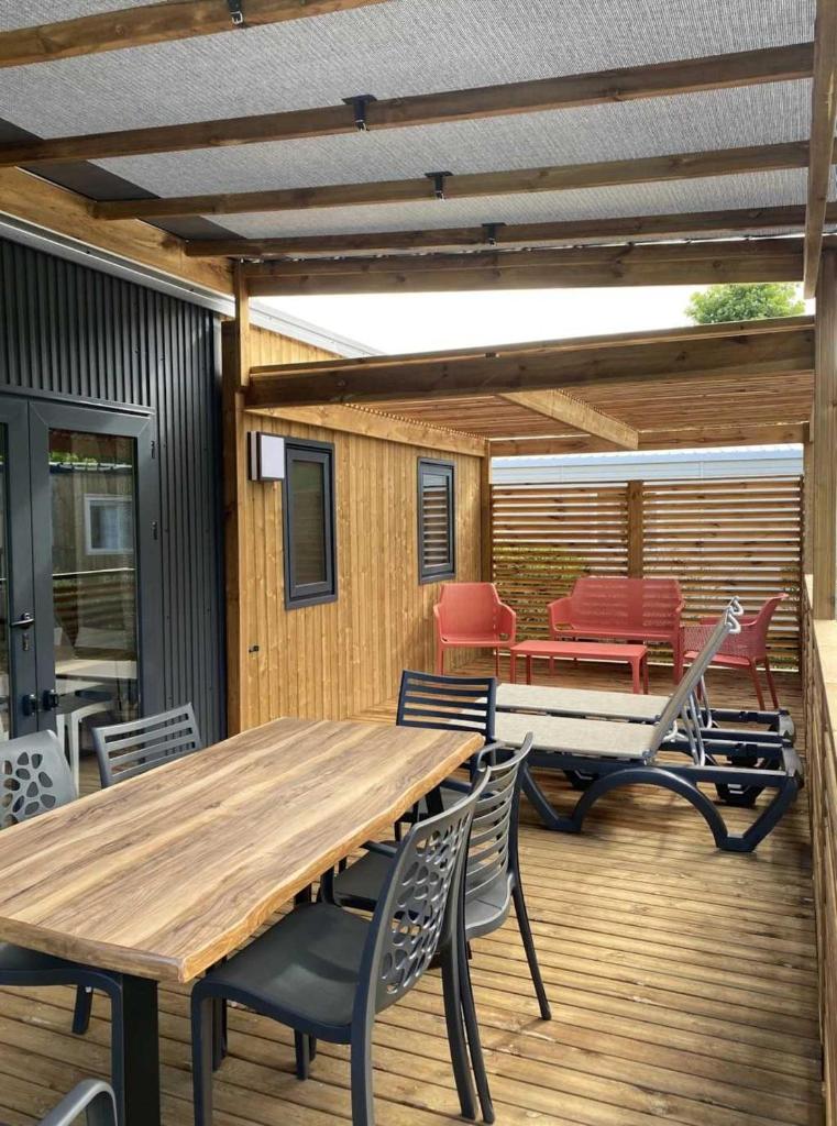 une terrasse avec une table et des chaises en bois. dans l'établissement Camping 4 étoiles - Parc aquatique - ccb0bcc, à Saint-Sauveur