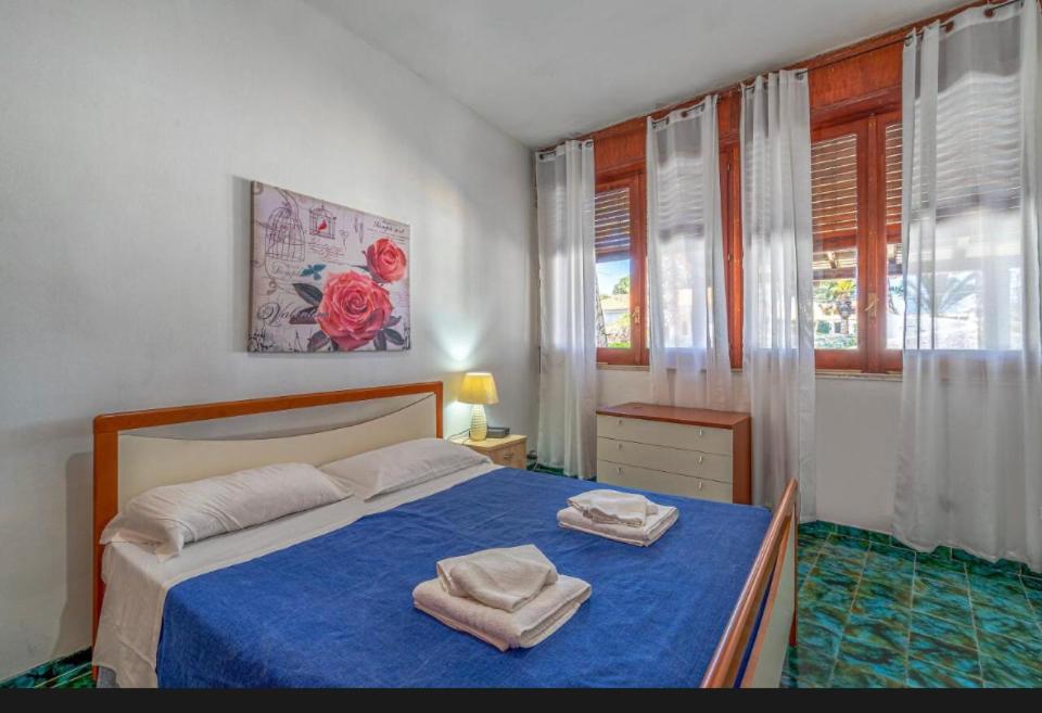 une chambre avec un lit bleu avec deux serviettes dessus dans l'établissement B&S Beach villa con piscina, à Fontane Bianche