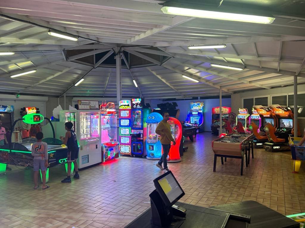 un groupe de personnes jouant à des jeux vidéo dans une salle d'arcade dans l'établissement Camping 5 étoiles en bord de mer Valras plage, à Vendres