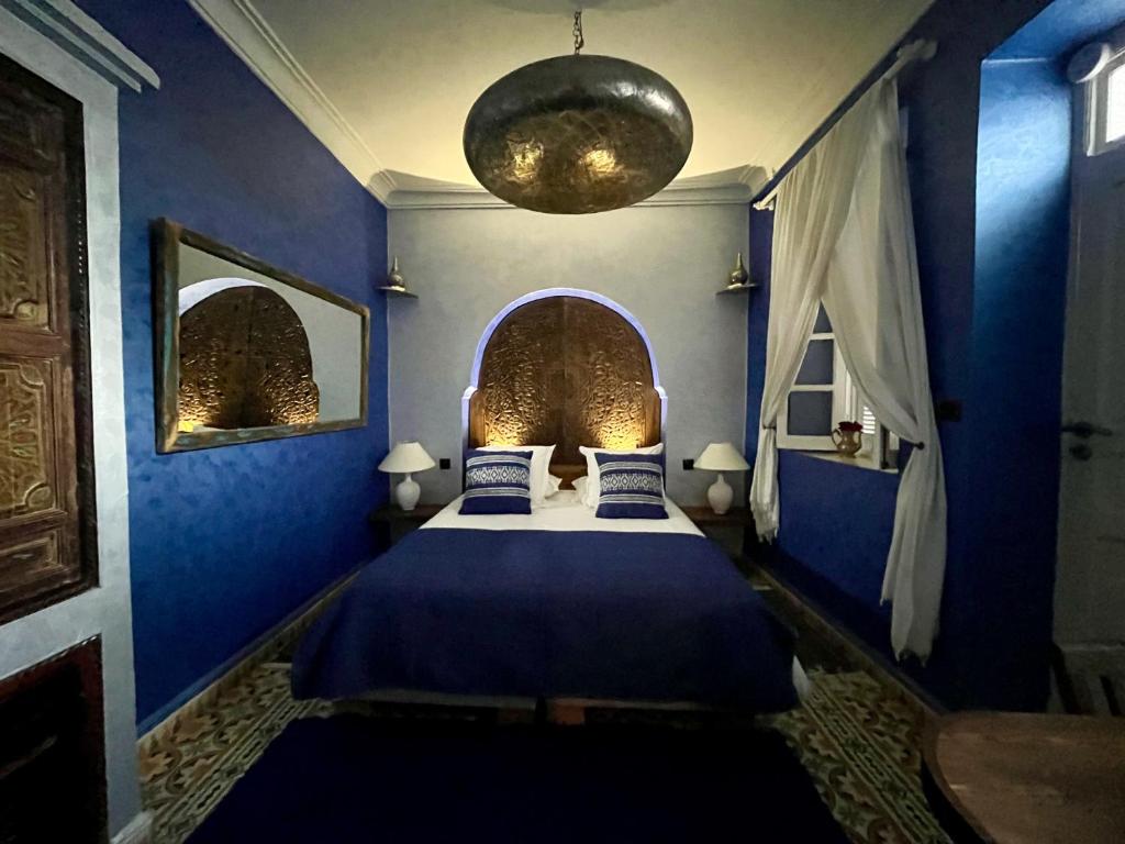 - une chambre avec des murs bleus et un lit avec des draps bleus dans l'établissement Riad MALAÏKA, à Essaouira