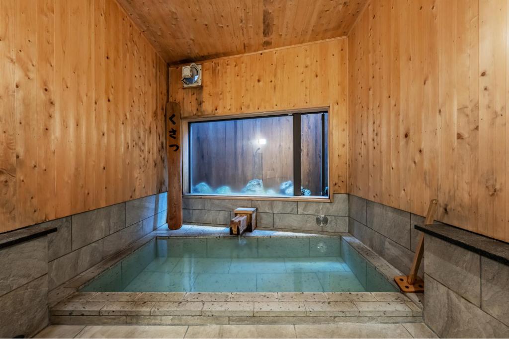 Cette chambre en bois dispose d'une baignoire et d'une fenêtre. dans l'établissement うり房旅館仲通り うら房, à Kusatsu