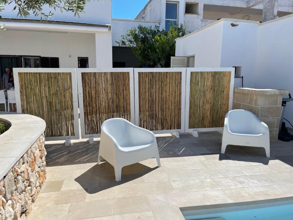 - deux chaises blanches sur une terrasse à côté d'une clôture dans l'établissement Le Liame Antico Trullo, à Gagliano del Capo