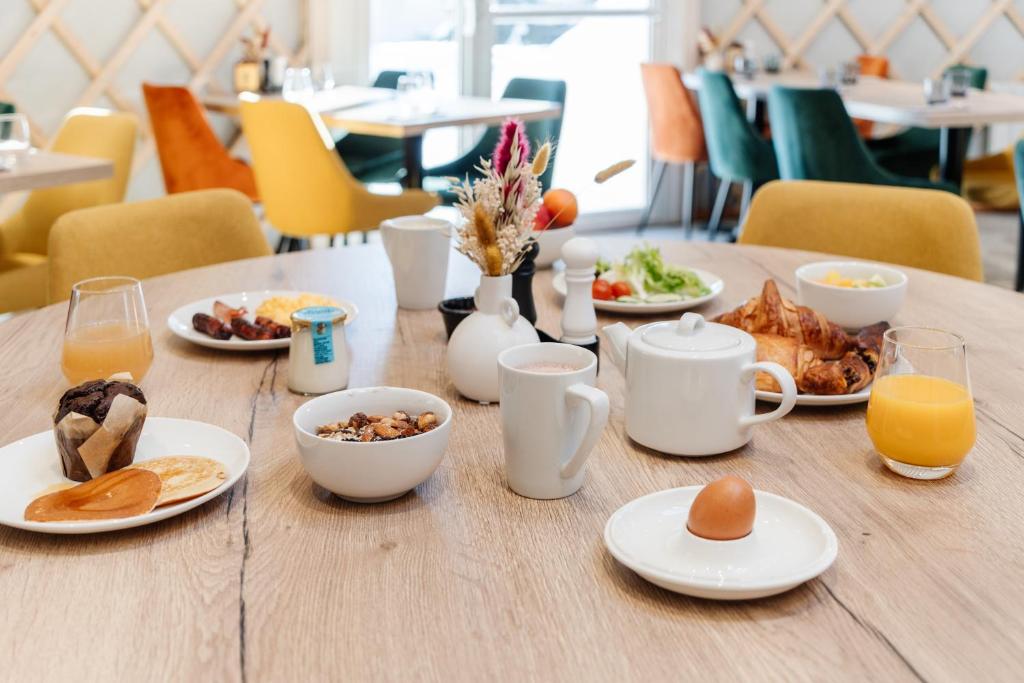 une table en bois avec des assiettes de nourriture et de jus d'orange dans l'établissement Lake Hotel Courchevel 1850, à Courchevel