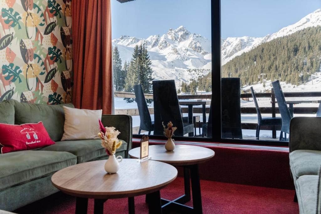 - un salon avec un canapé, 2 tables et une fenêtre dans l'établissement Lake Hotel Courchevel 1850, à Courchevel
