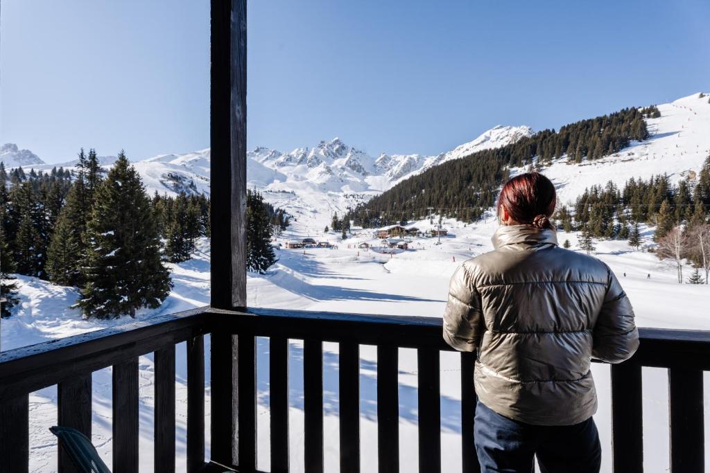 une femme debout sur un balcon donnant sur les montagnes dans l'établissement Lake Hotel Courchevel 1850, à Courchevel 32 autres photos