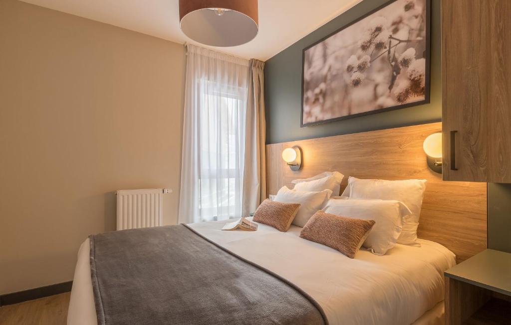 une chambre avec un grand lit avec des oreillers blancs dans l'établissement Résidence Odalys L'Ecrin de Vars, à Vars 14 autres photos