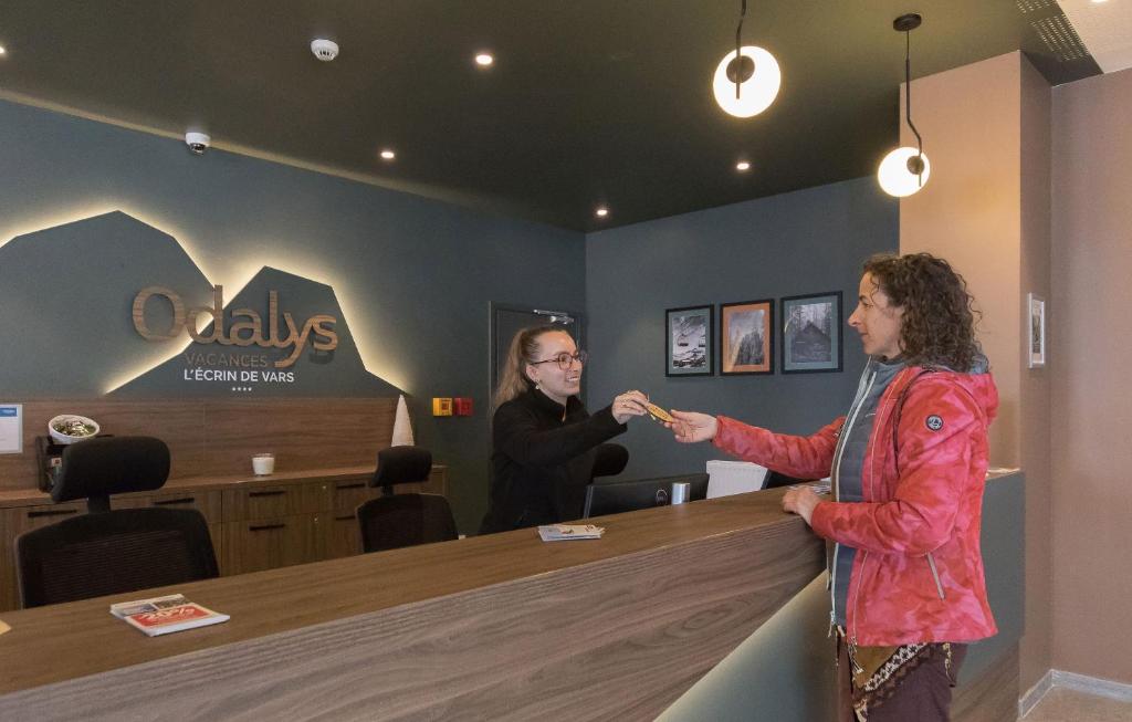 un homme et une femme debout dans une salle d'attente dans l'établissement Résidence Odalys L'Ecrin de Vars, à Vars