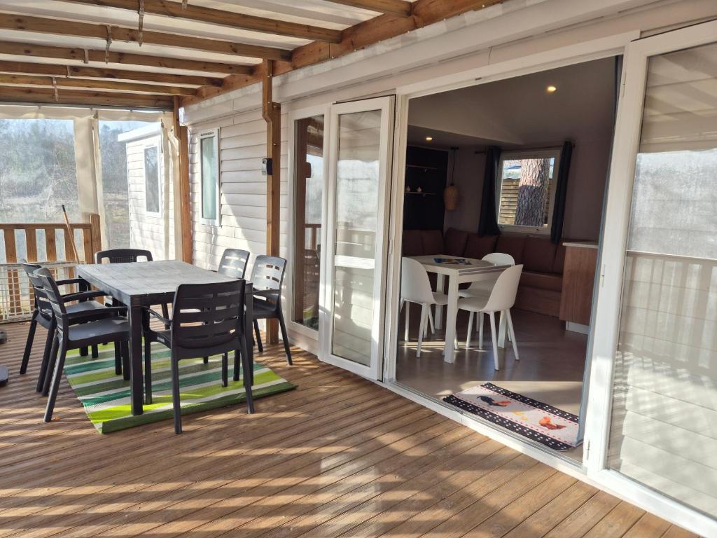 une véranda avec une table et des chaises dans l'établissement MH 201 AGREABLE et tout ÉQUIPÉ 2CH dont suite parentale et 2sdb avec vue sur foret dans camping 4 étoiles, à Saint-Julien-en-Born