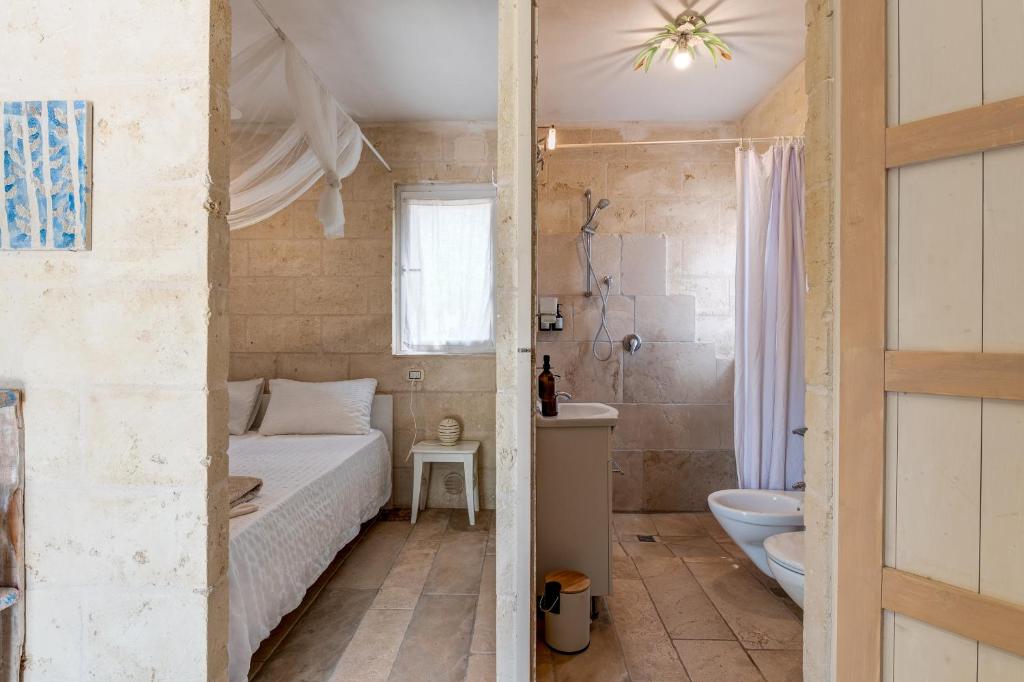 - une chambre avec un lit, des toilettes et une salle de bains dans l'établissement VILLA OSTUNI ONE mit Pool, Gästehaus & Glamping, à Ostuni