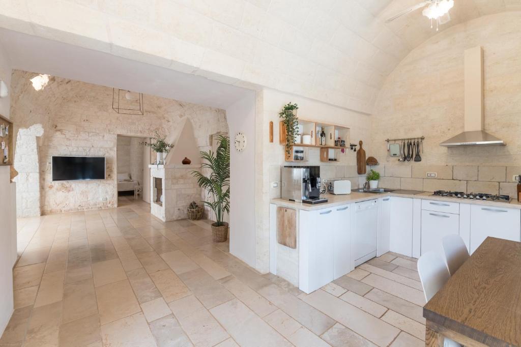une grande cuisine avec des placards blancs et un mur en pierre dans l'établissement VILLA OSTUNI ONE mit Pool, Gästehaus & Glamping, à Ostuni
