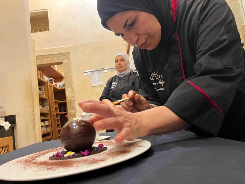 une femme prépare un dessert sur une assiette dans l'établissement Riad MALAÏKA, à Essaouira