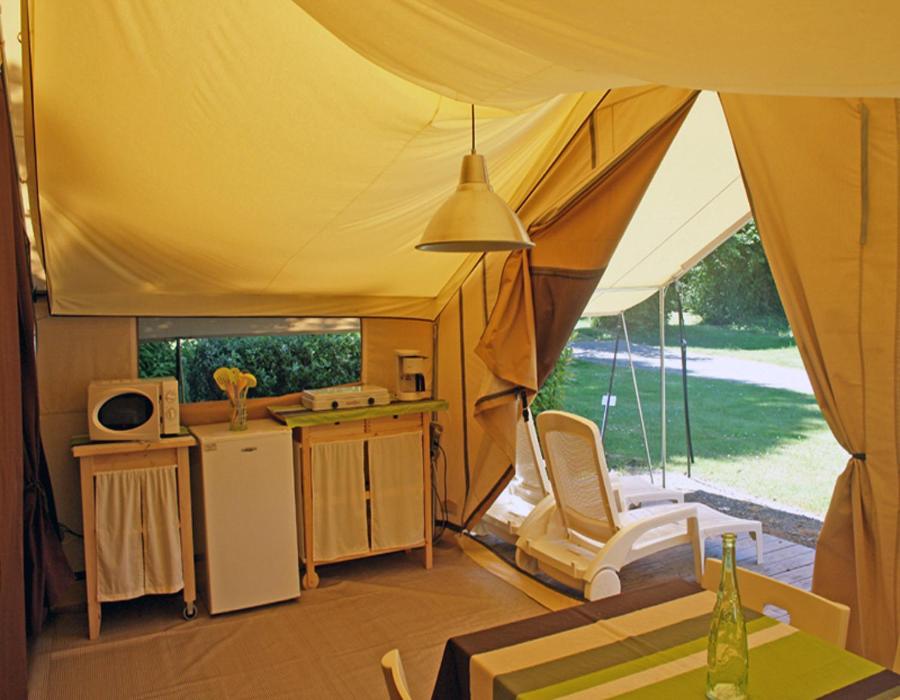 Cette tente comprend une cuisine, une table et une chaise. dans l'établissement Camping Le Moulin des Effres, à Secondigny