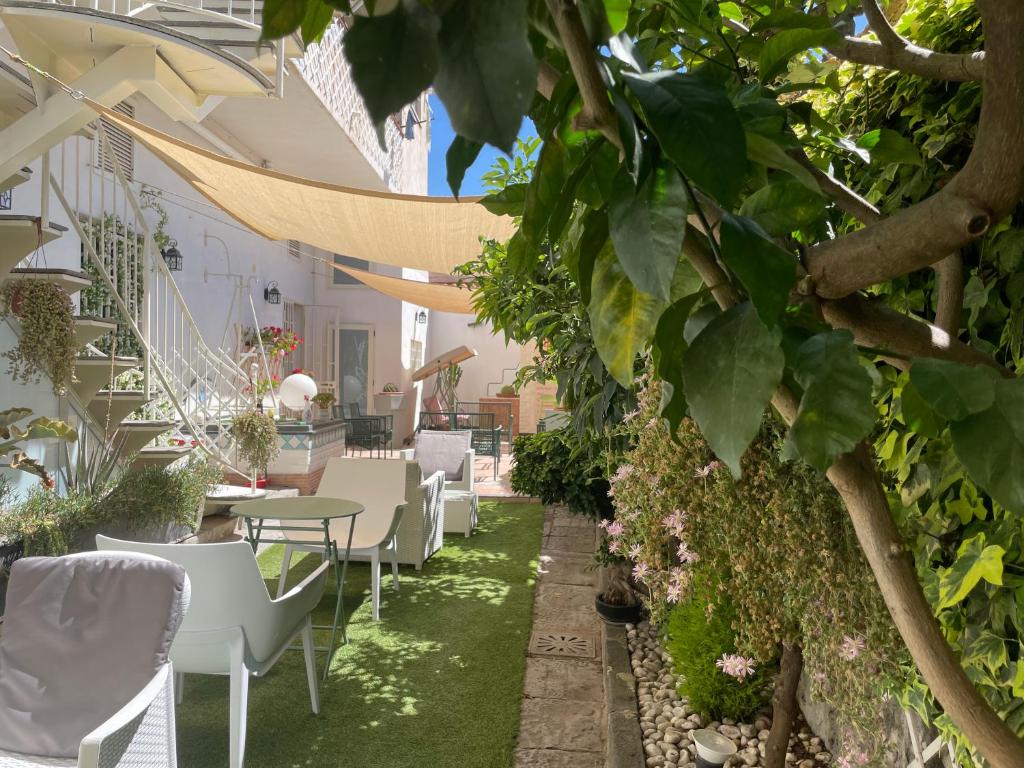 un patio avec des chaises blanches, des tables et des plantes dans l'établissement Pompei Home & Green Luxury Apartment, à Boscoreale