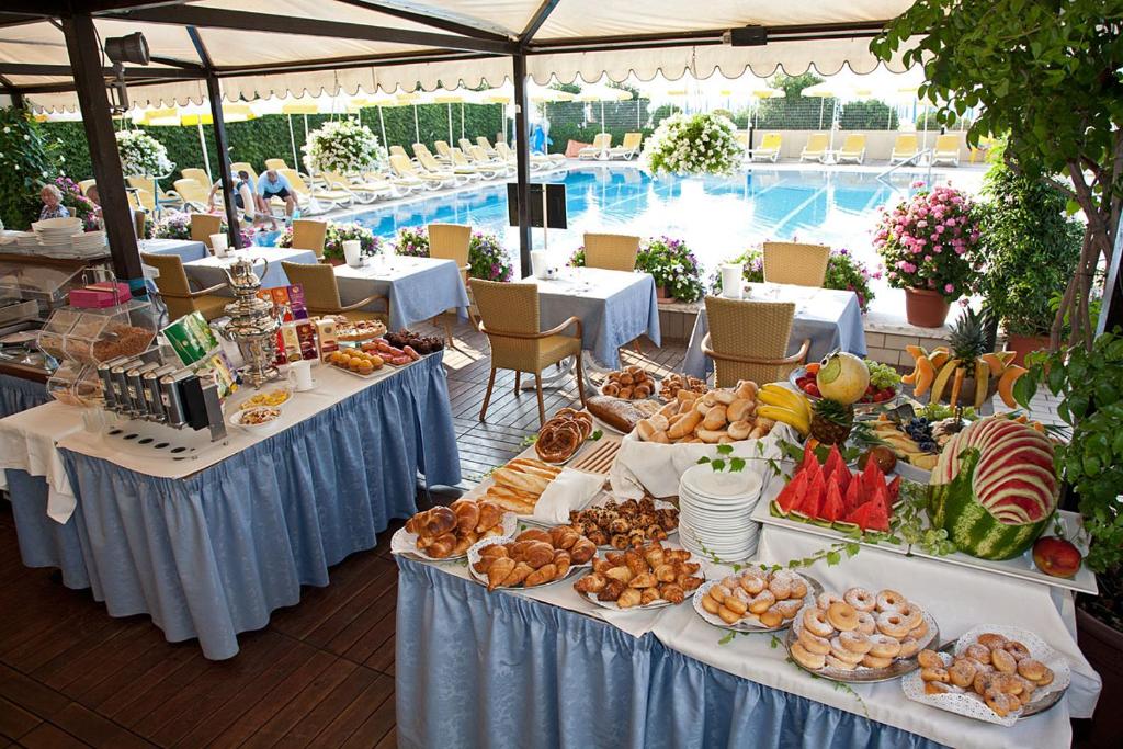 - un buffet de plats sur les tables en face de la piscine dans l'établissement Hotel Sirenetta, à Lido di Jesolo