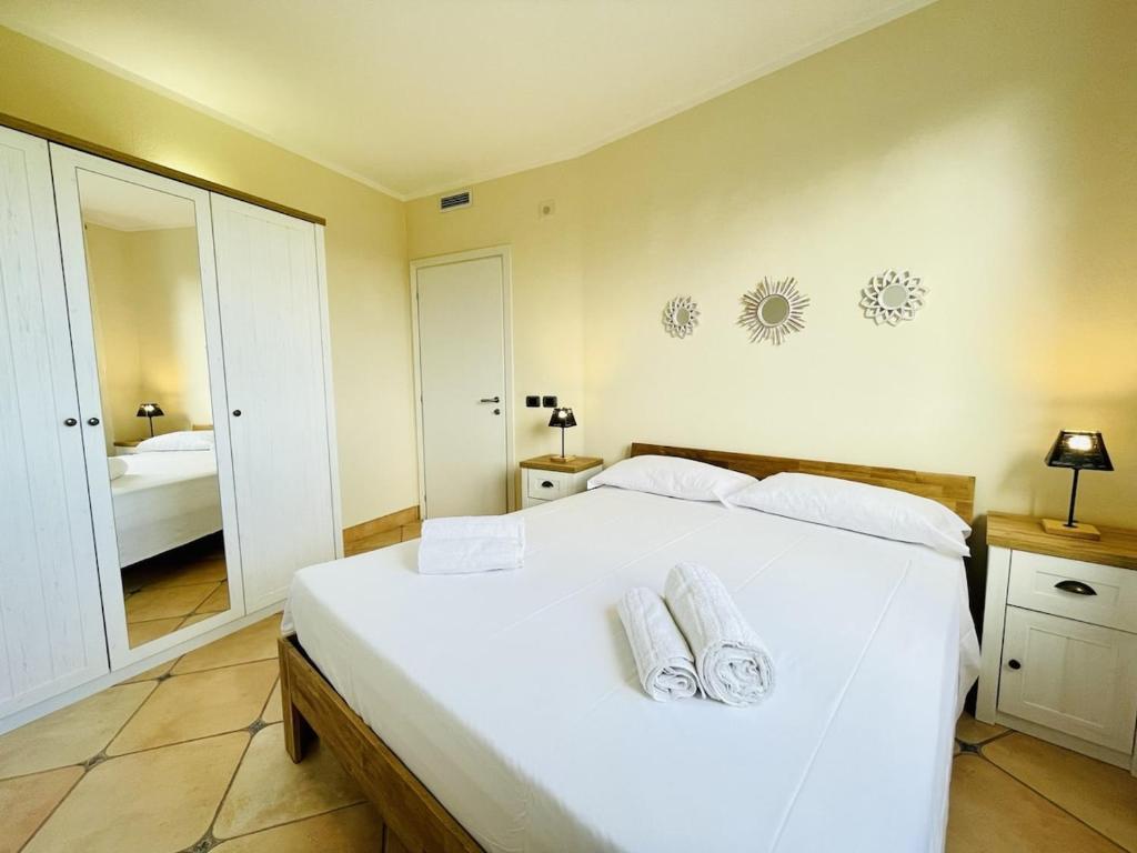 une chambre avec un grand lit blanc avec deux serviettes dans l'établissement Villa esclusiva con piscina privata e vista mare, à San Michele
