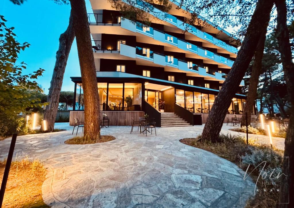 - un bâtiment avec une terrasse en face dans l'établissement HOTEL NOIR - Free Brunch & Breakfast Until 13-00 - Vicinissimi a Mirabilandia, à Milano Marittima