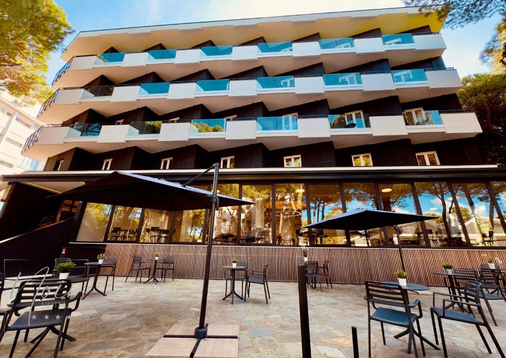 un restaurant avec des tables et des parasols en face d'un bâtiment dans l'établissement HOTEL NOIR - Free Brunch & Breakfast Until 13-00 - Vicinissimi a Mirabilandia, à Milano Marittima