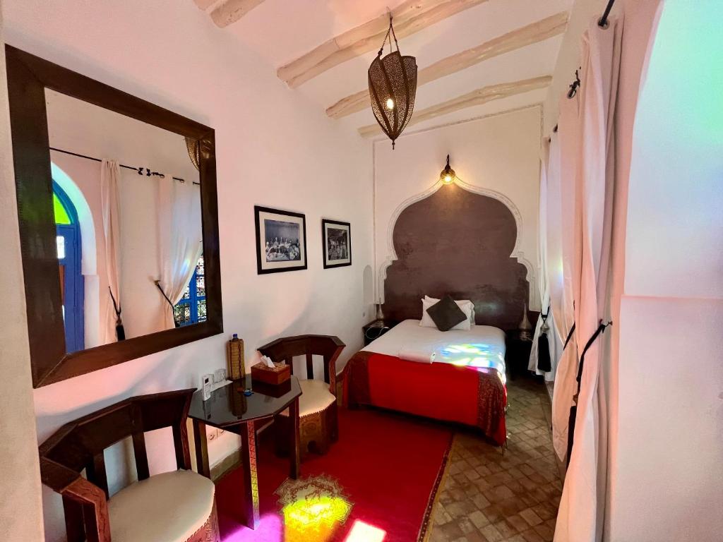 une chambre avec un lit, une table et un miroir dans l'établissement Riad Chameleon, à Marrakech 37 autres photos