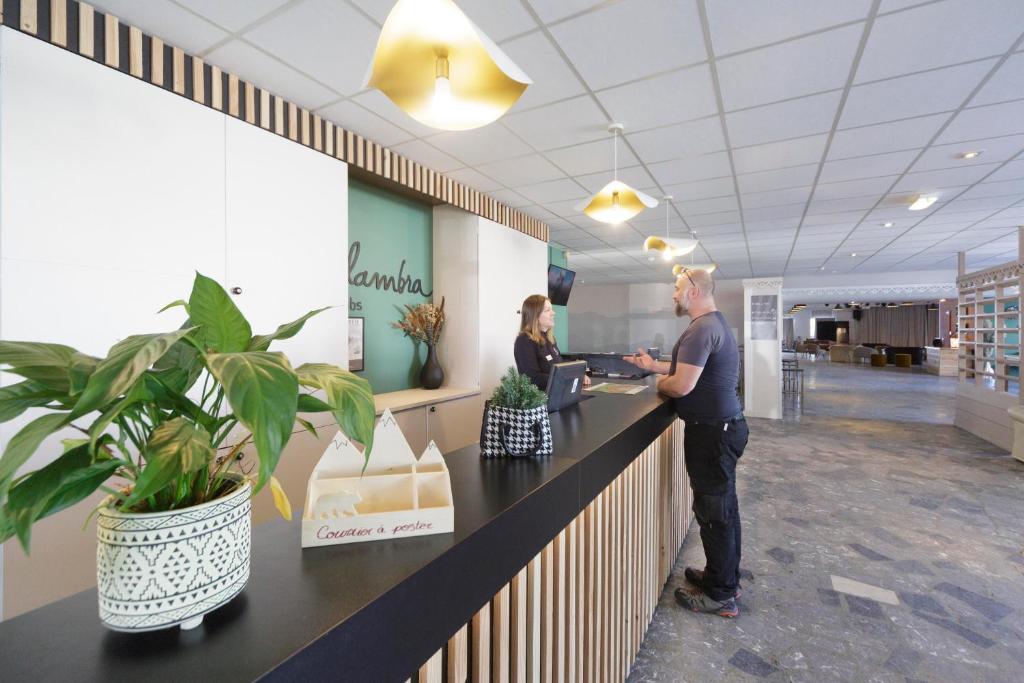 Un homme et une femme se tenant au comptoir d'un bureau dans l'établissement Belambra Clubs Gourette - Lou Sarri, à Gourette