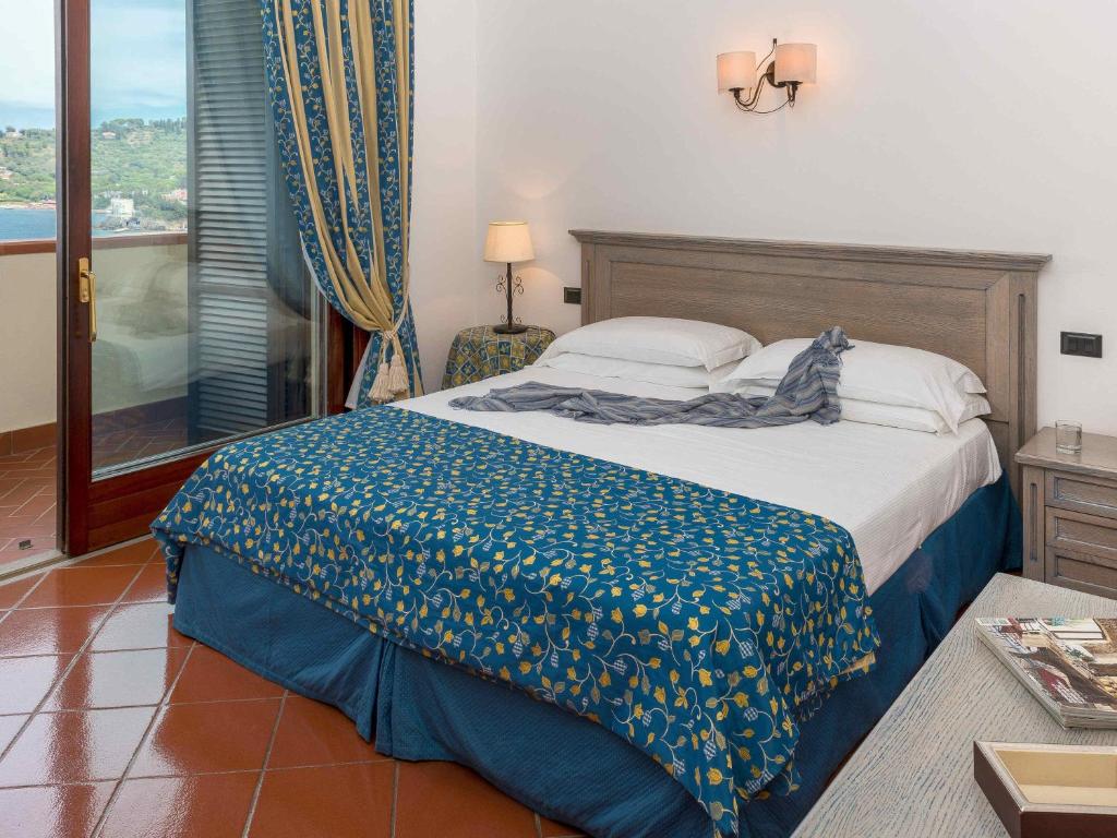 - une chambre avec un lit doté d'une couverture bleue dans l'établissement Albergo Filippo II, à Porto Santo Stefano