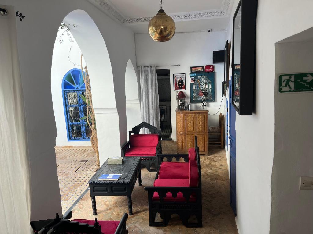 un salon avec des chaises rouges et une table dans l'établissement Riad Chameleon, à Marrakech