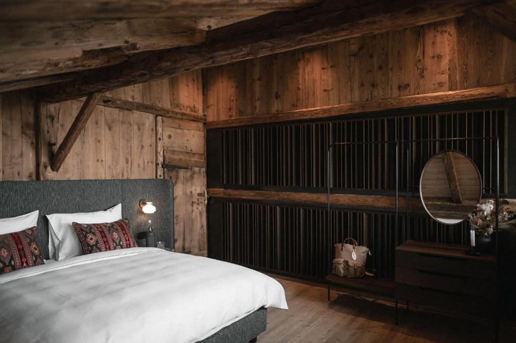 une chambre avec un grand lit et des murs en bois dans l'établissement Felder Alpin Lodge, à Villandro