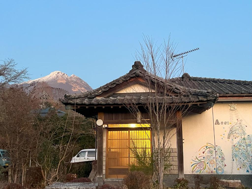 une petite maison avec une montagne en arrière-plan dans l'établissement Assi House, à Yufu