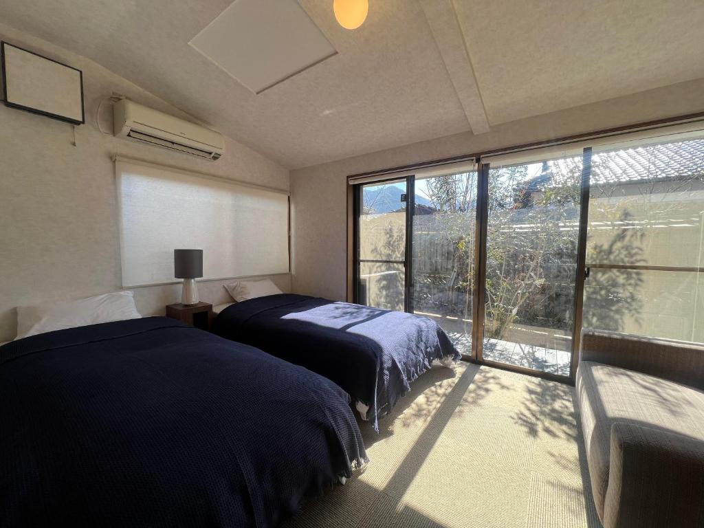 une chambre avec deux lits et une grande fenêtre dans l'établissement Assi House, à Yufu