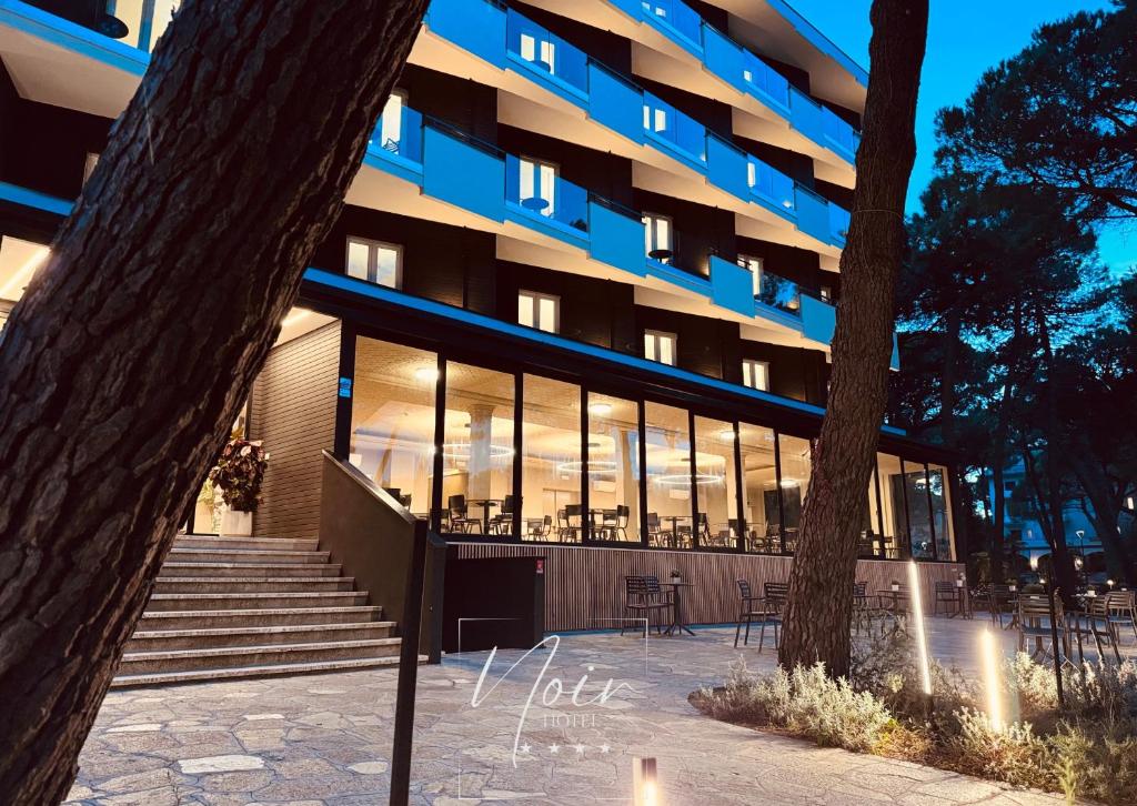 un bâtiment avec des tables et des chaises devant lui dans l'établissement HOTEL NOIR - Free Brunch & Breakfast Until 13-00 - Vicinissimi a Mirabilandia, à Milano Marittima