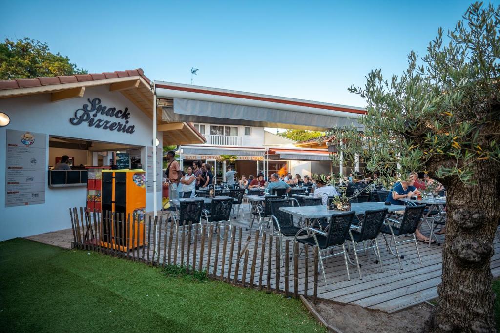 un restaurant avec des tables et des chaises sur une terrasse dans l'établissement Camping Lou Pignada, à Messanges